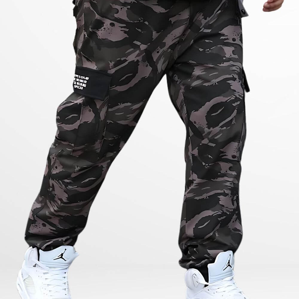 Man wearing baggy camo cargo pants paired with white high-top sneakers, showcasing a modern streetwear style with a gray and black camouflage pattern.