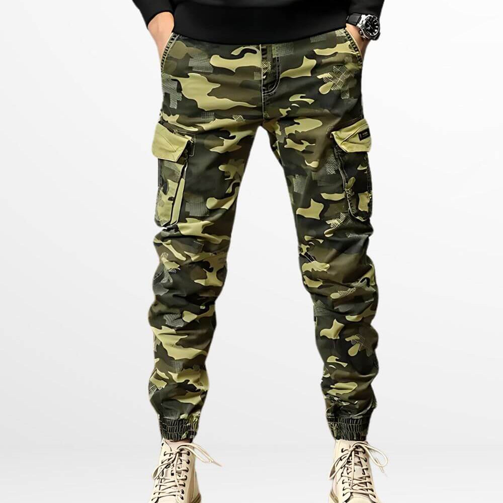 Man sporting stylish green camo cargo pants paired with cream high-top sneakers, featuring a multitude of pockets and a snug fit at the ankles.