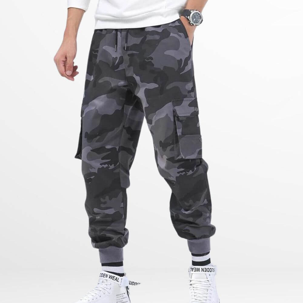 Man in grey camo cargo pants paired with white high-top sneakers, featuring a relaxed fit and stylish streetwear look with practical pockets.