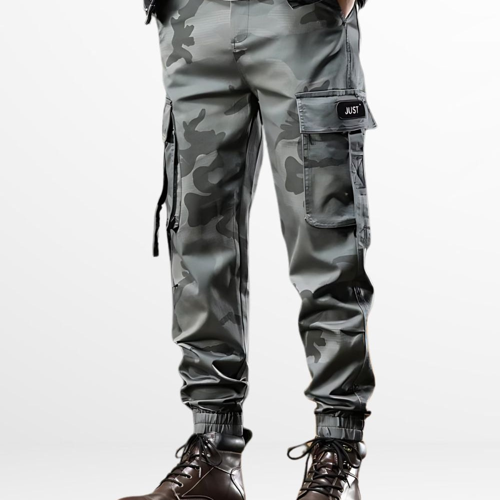 Man sporting men's camo cargo pants in a grey camouflage pattern, paired with dark brown leather boots, perfect for both tactical use and streetwear.