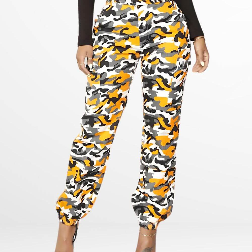 Woman wearing vibrant orange camo cargo pants, paired with a black top and clear heeled sandals, showcasing a bold and stylish look with a multicolor camouflage pattern.