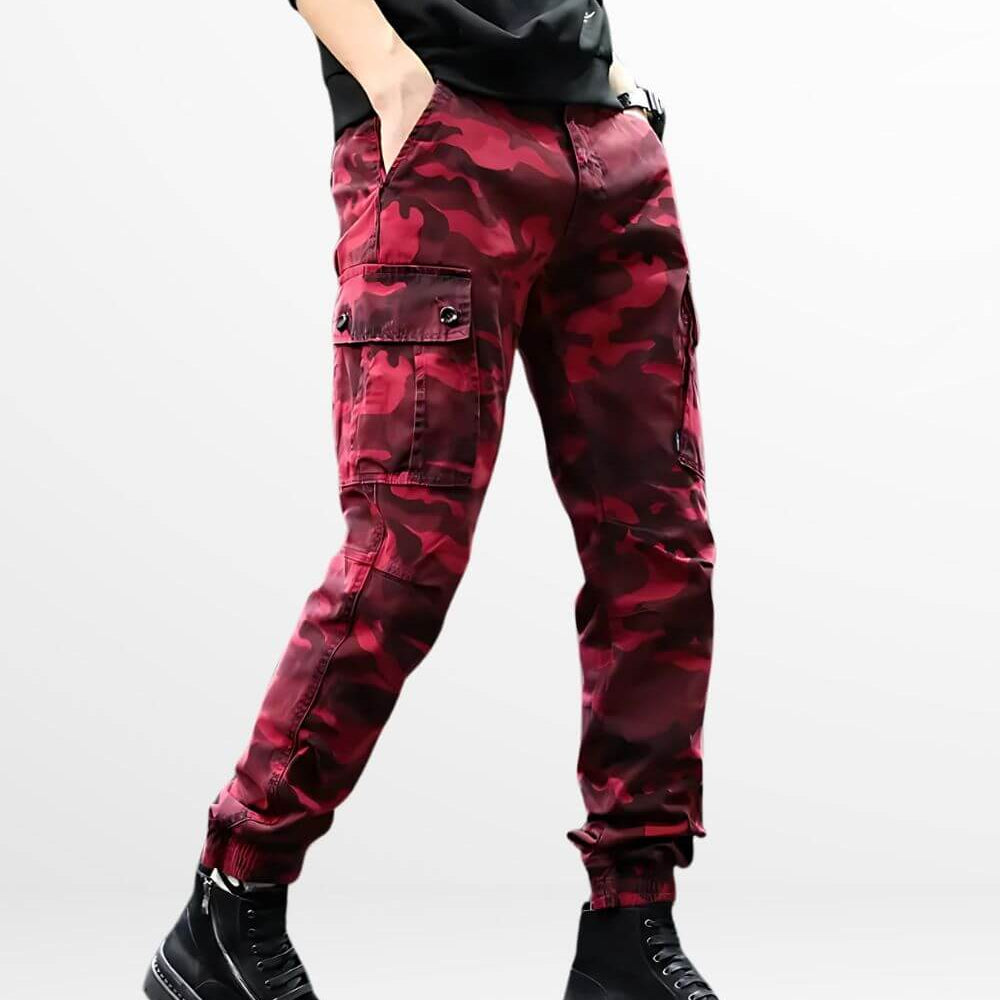 Man wearing fashionable red camo cargo pants paired with black combat boots, showcasing a bold, contemporary look with utility pockets.