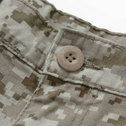 Macro shot of a button closure on military desert camo pants, emphasizing the detailed stitching and camouflage pattern.