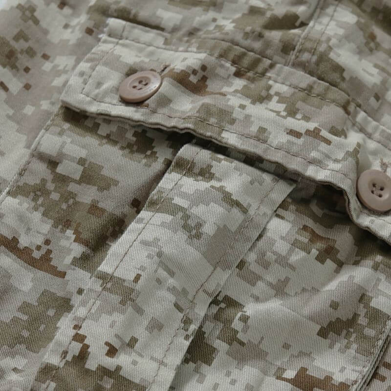 Close-up of the military desert camo pants pockets showing the fabric texture, pattern detail, and buttoned pocket flaps.