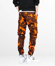 Back view of camo and orange cargo pants showing pocket details, styled with white high-top sneakers for urban streetwear flair.