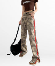 Casual look featuring baggy camo cargo pants for women with a red side stripe, complete with a black shoulder bag and casual footwear.