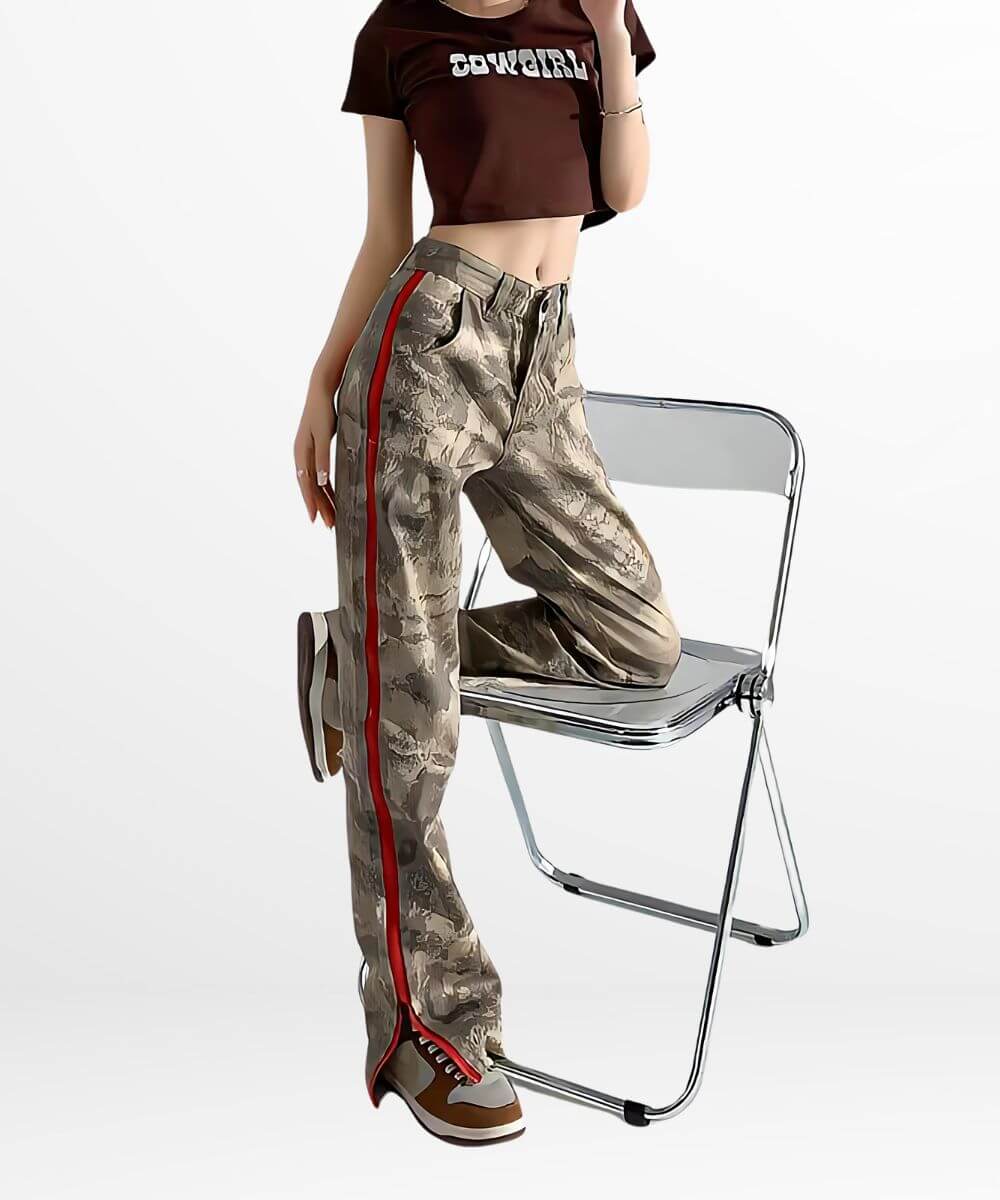 Woman seated on a chair in stylish baggy camo cargo pants with a red stripe, paired with a brown crop top and brown sneakers