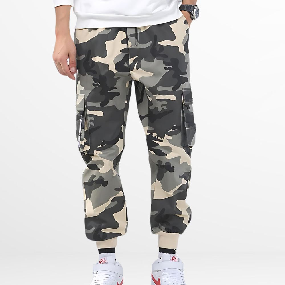 Front view of a man wearing baggy camo pants for a casual, relaxed fit, with hands in pockets and paired with white sneakers.