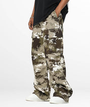 Side walking pose showing the flow of baggy camouflage pants with white sneakers.