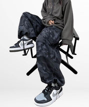 A seated woman showcasing the relaxed fit of baggy camouflage pants, complete with stylish high-top sneakers.