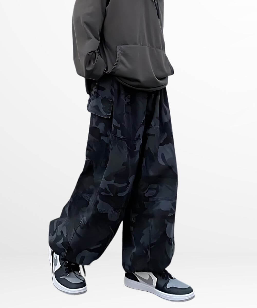 Side view of a woman standing in baggy camouflage pants paired with trendy black and white sneakers.