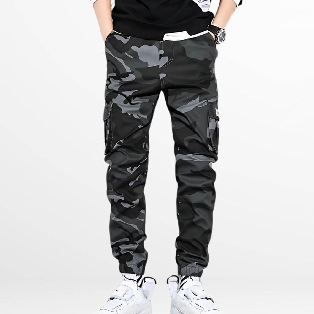 Front view of a man standing in black and gray camo cargo pants, featuring the pants' sleek design and cargo pockets.