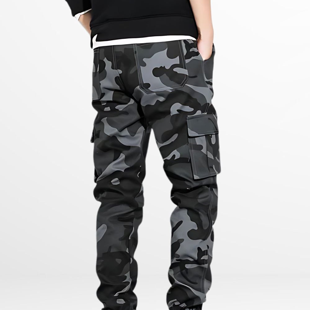 Rear view of a man wearing black and gray camo cargo pants, highlighting the back pocket and comfortable elastic cuffs.