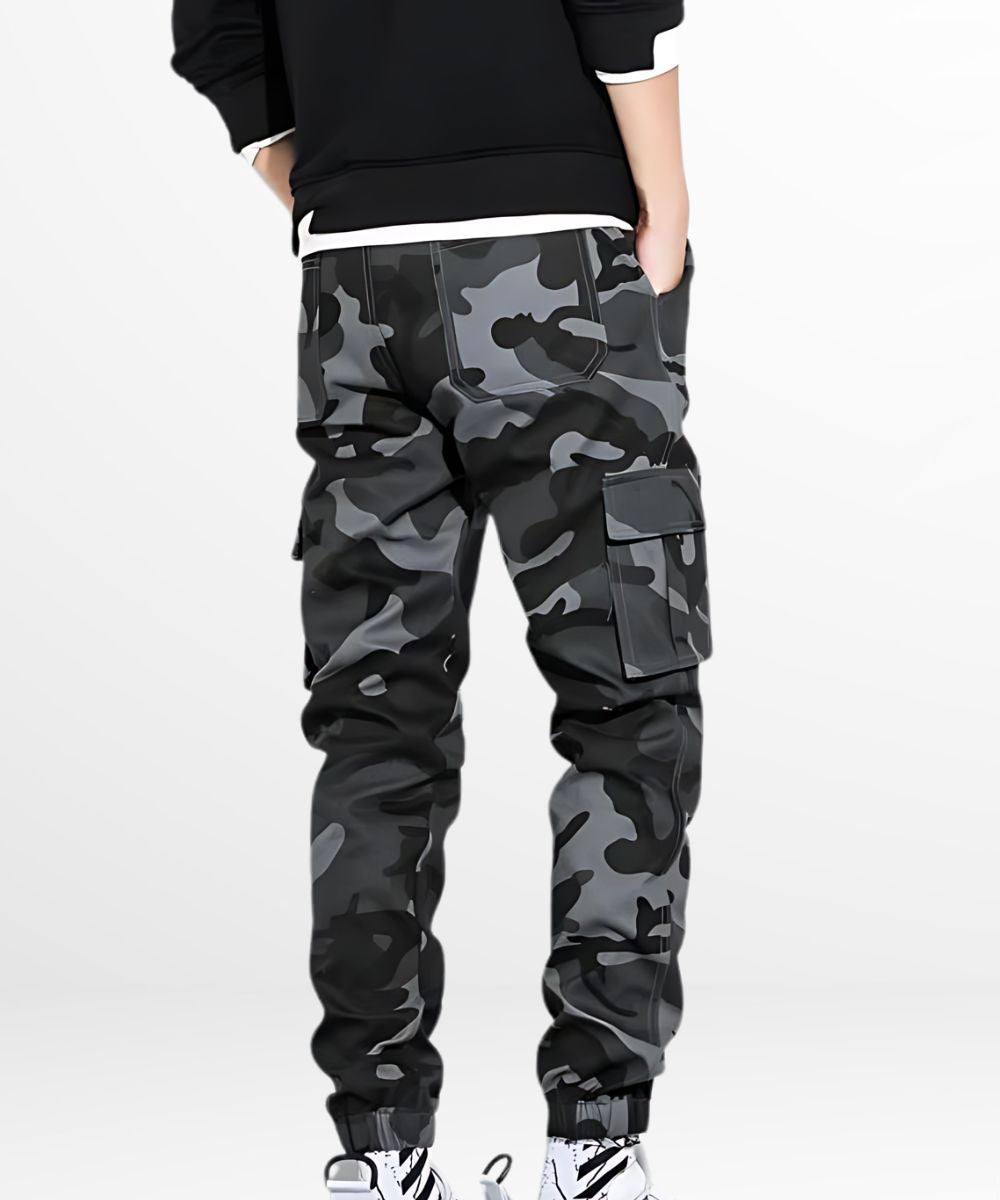 Rear view of a man wearing black and gray camo cargo pants, highlighting the back pocket and comfortable elastic cuffs.