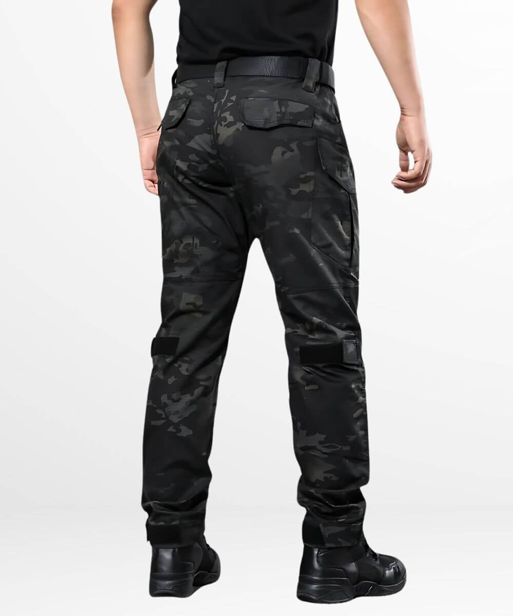 Back view of a man wearing black camo combat pants, highlighting the utility pockets and rugged design for outdoor activities.