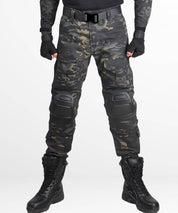 Front view of black camo hunting pants with knee pads and tactical boots.