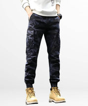 Top-down view of men's tapered blue camouflage pants showcasing cargo pockets and belt detail.