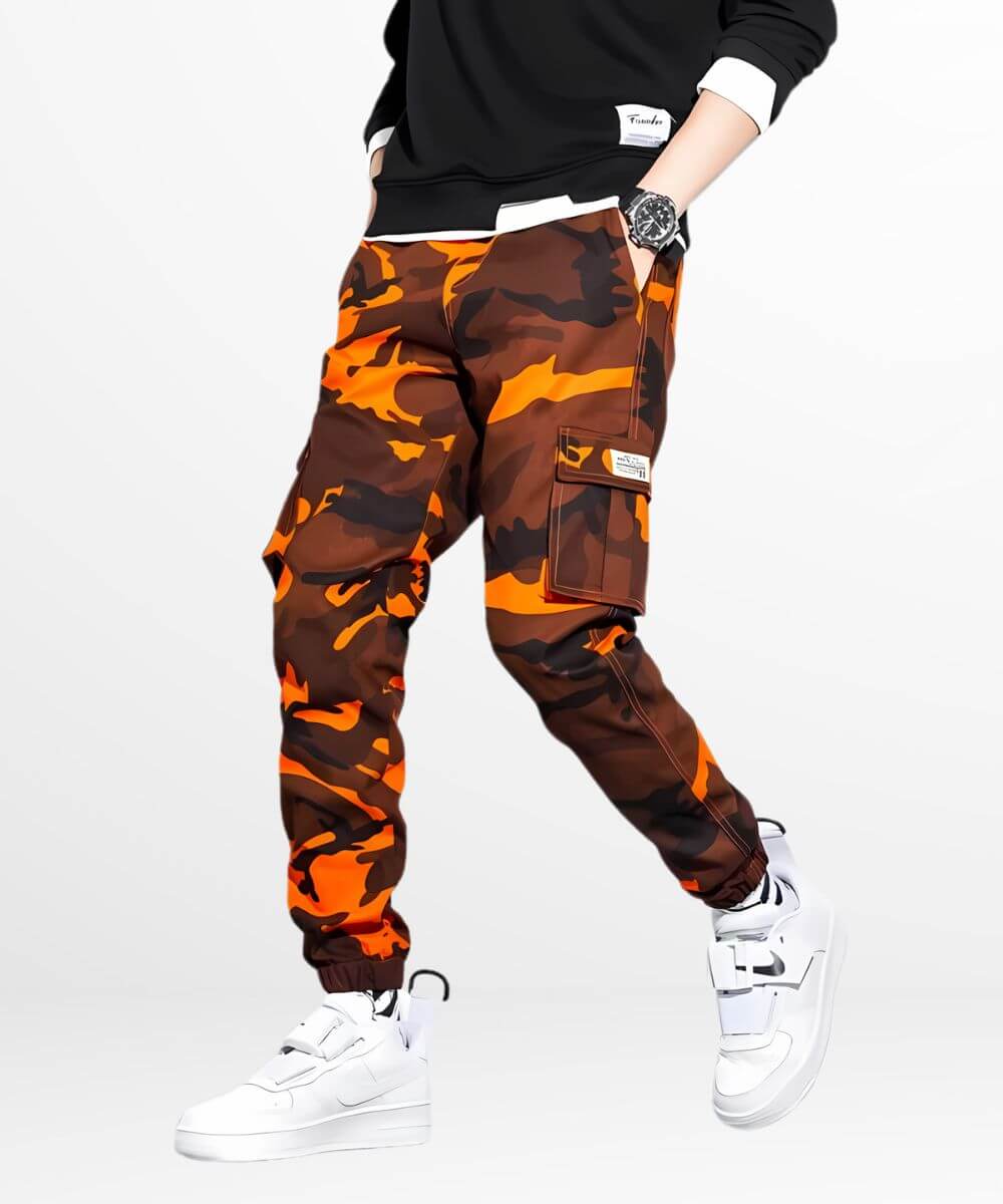 A side view of a dynamic pose in camo and orange cargo pants, highlighting the vivid color scheme and relaxed fit.