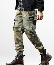 Casual walking pose featuring camo green cargo pants for men, combined with brown boots for a streetwear vibe.