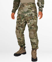 Front view of men's camo hunting pants with integrated knee pads and tactical boots.