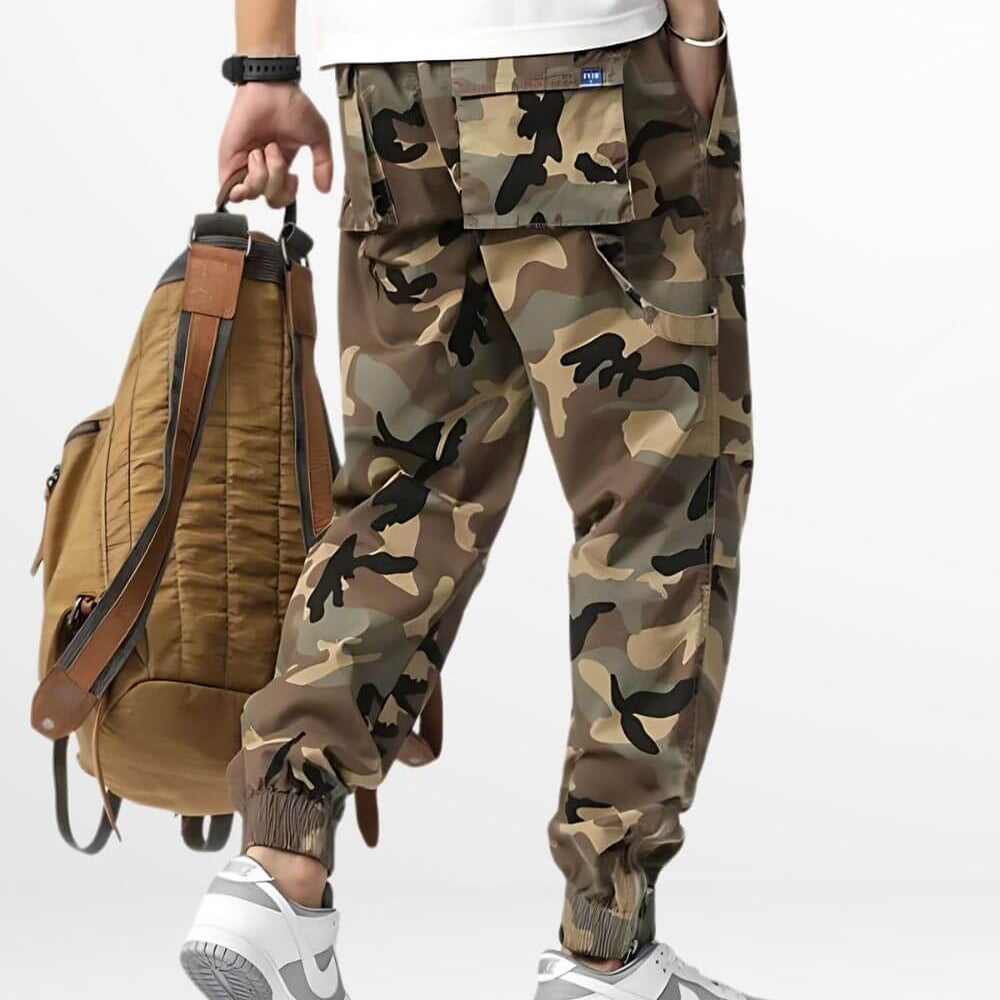 Side view of a person dressed in stylish camouflage cargo pants with a brown leather backpack, highlighting a modern urban fashion ensemble.