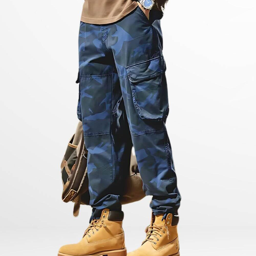Men's dark blue camo pants paired with classic tan work boots and a brown leather bag, perfect for a streetwear-inspired look.