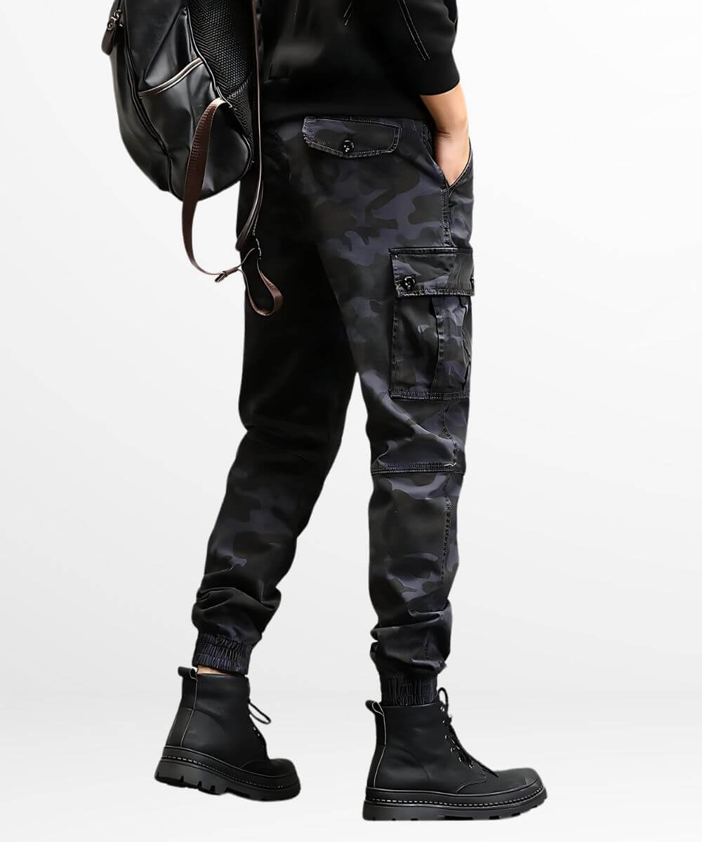 Rear view of dark grey camo cargo slim-fit pants on a man, highlighting the detailed back pocket and overall fit with a stylish leather backpack.
