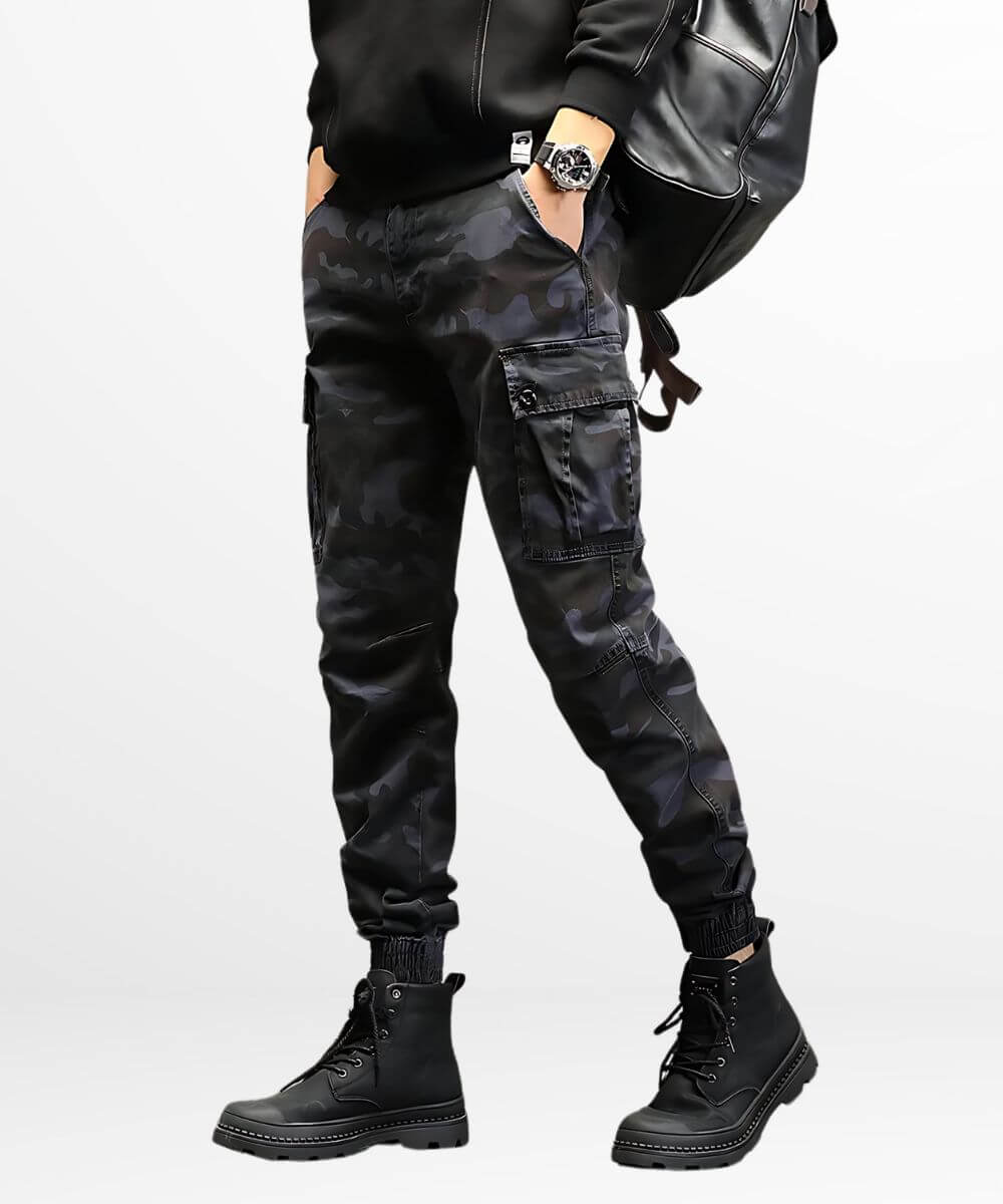 Man wearing dark grey camo cargo slim-fit pants with a casual black t-shirt and black combat boots, showcasing street-style fashion.