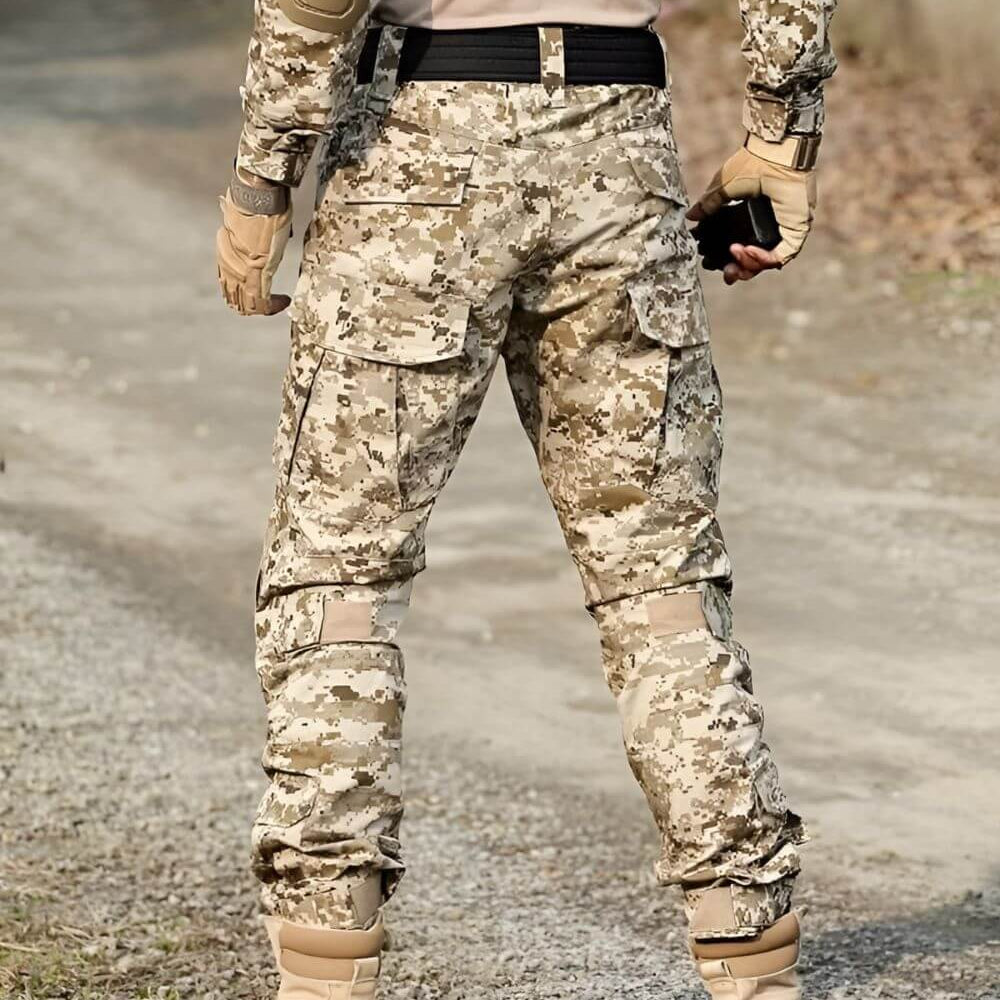 Back view of desert camo pants for men in an outdoor setting, showcasing the adaptive camouflage and tactical pockets for utility.