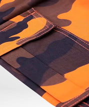 Detailed view of the utility pocket on camo and orange cargo pants, emphasizing the functional design and bold color palette.