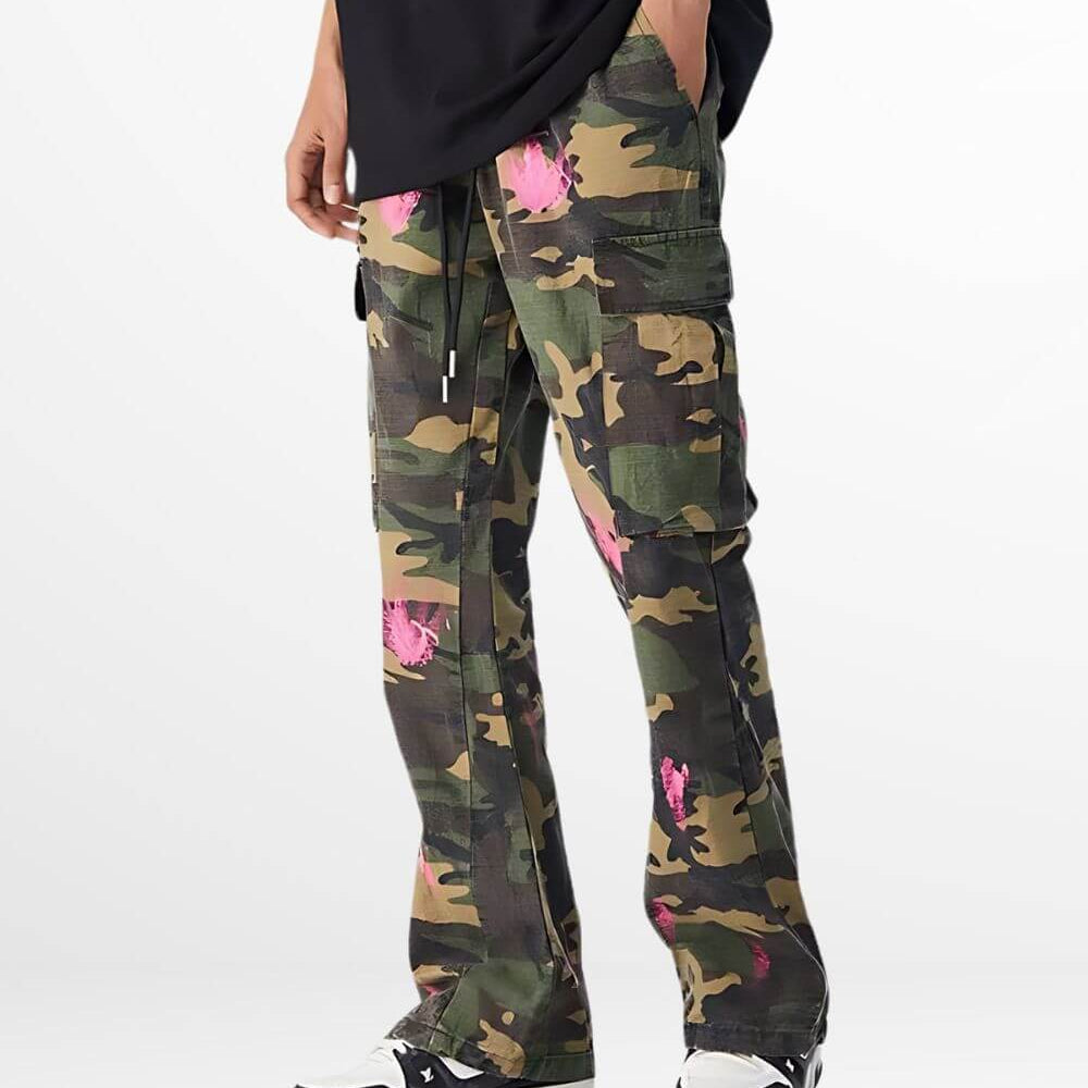 Side view of green and pink camouflage pants with pockets, worn with black sneakers.