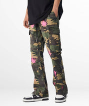Side view of green and pink camouflage pants with pockets, worn with black sneakers.