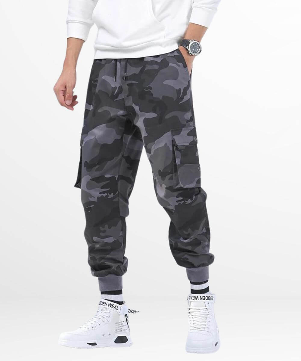 Man in grey camo cargo pants paired with white high-top sneakers, featuring a stylish urban look with practical cargo pockets and a contemporary camouflage design.