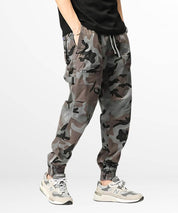 A stylish individual showcasing grey camo cargo sweatpants complemented by a black top and trendy sneakers, perfect for a modern street style look.