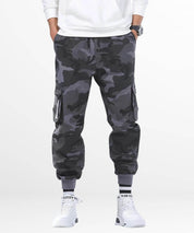 Front view of grey camo pants mens with one hand in the rear pocket, showcasing the pants' practical design and fit.