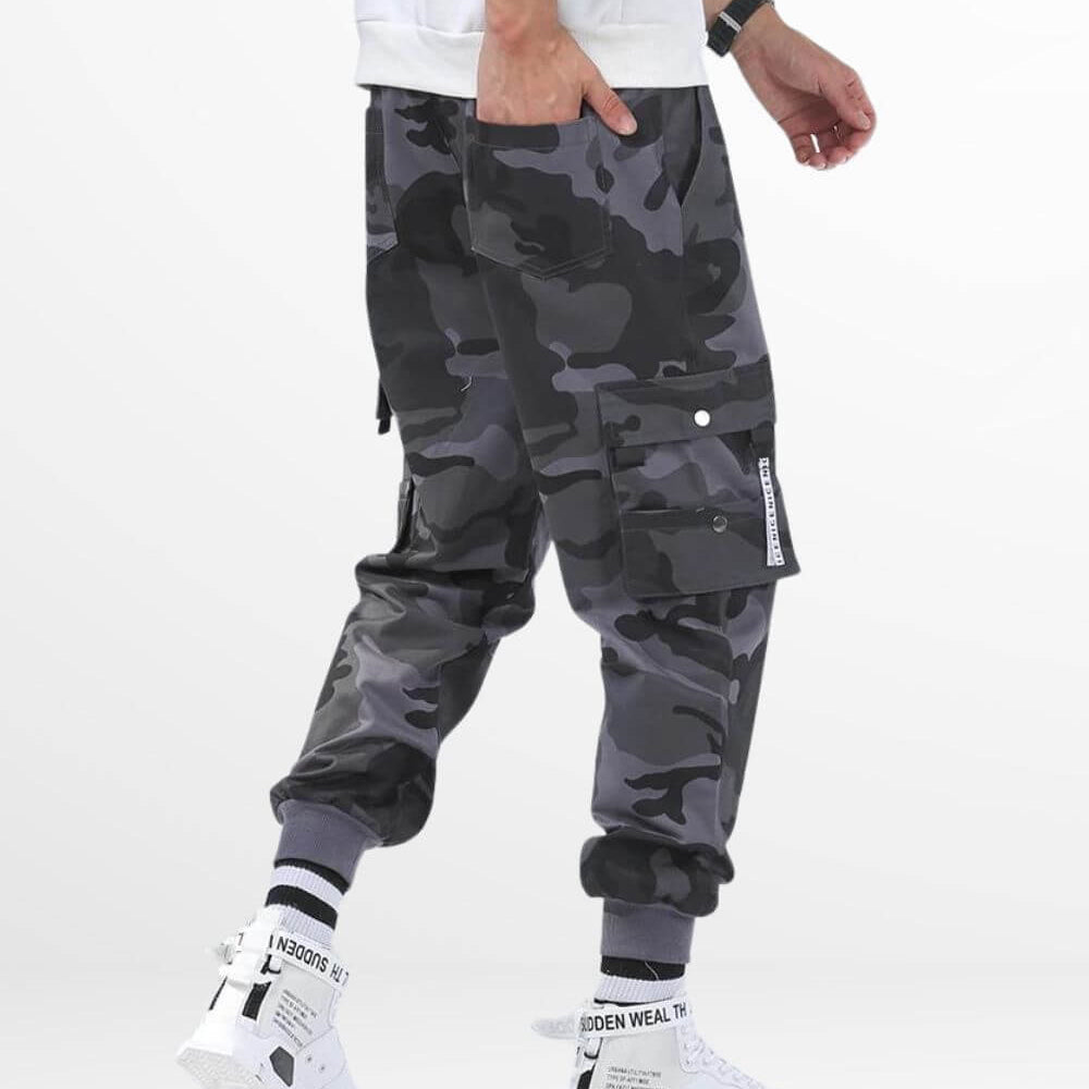 Side view showing the pocket detail of grey camo pants mens with a hand inserted, complemented by white sneakers.