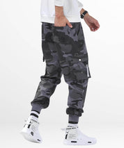 Side view showing the pocket detail of grey camo pants mens with a hand inserted, complemented by white sneakers.