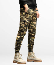 Side angle highlighting the utility pockets on men's slim-fit khaki camo cargo pants with beige combat boots.