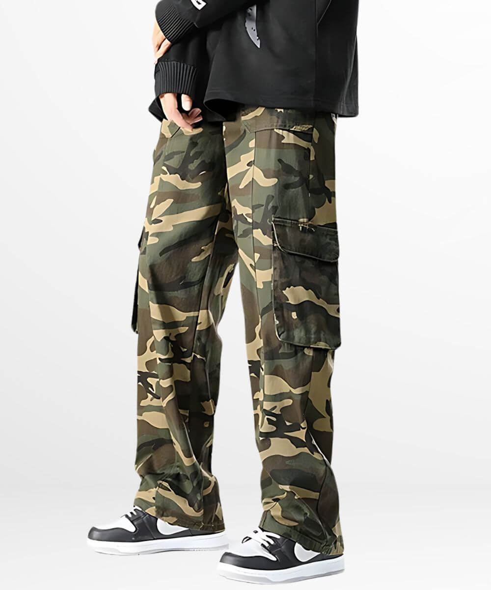 Men's baggy camo cargo pants styled with classic black and white sneakers, paired with a black sweater for a relaxed urban look.