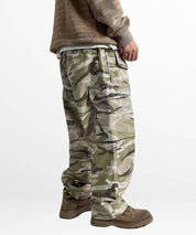 Side view of a man modeling men's baggy camo pants, focusing on the ample pocket space and the comfortable, relaxed fit for outdoor wear.
