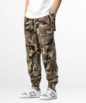 Man wearing camouflage cargo sweatpants paired with white sneakers and a simple white t-shirt, showcasing a casual and trendy streetwear look.