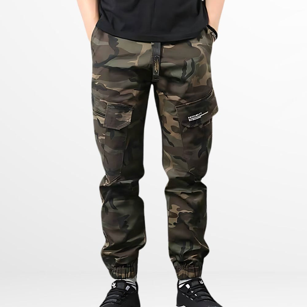 A man sporting relaxed-fit men's cargo camo pants with a casual style, standing front view with white sneakers.