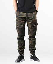 A man sporting relaxed-fit men's cargo camo pants with a casual style, standing front view with white sneakers.