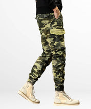 Casual green camouflage cargo pants for men showing pocket details and matching high-top sneakers.