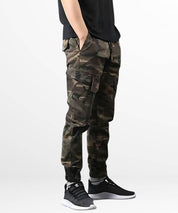 Full-length image showing the stylish fit of men's cargo camo pants paired with white high-top sneakers.