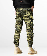 Side view of trendy green camouflage cargo pants for men, paired with cream high-top sneakers.