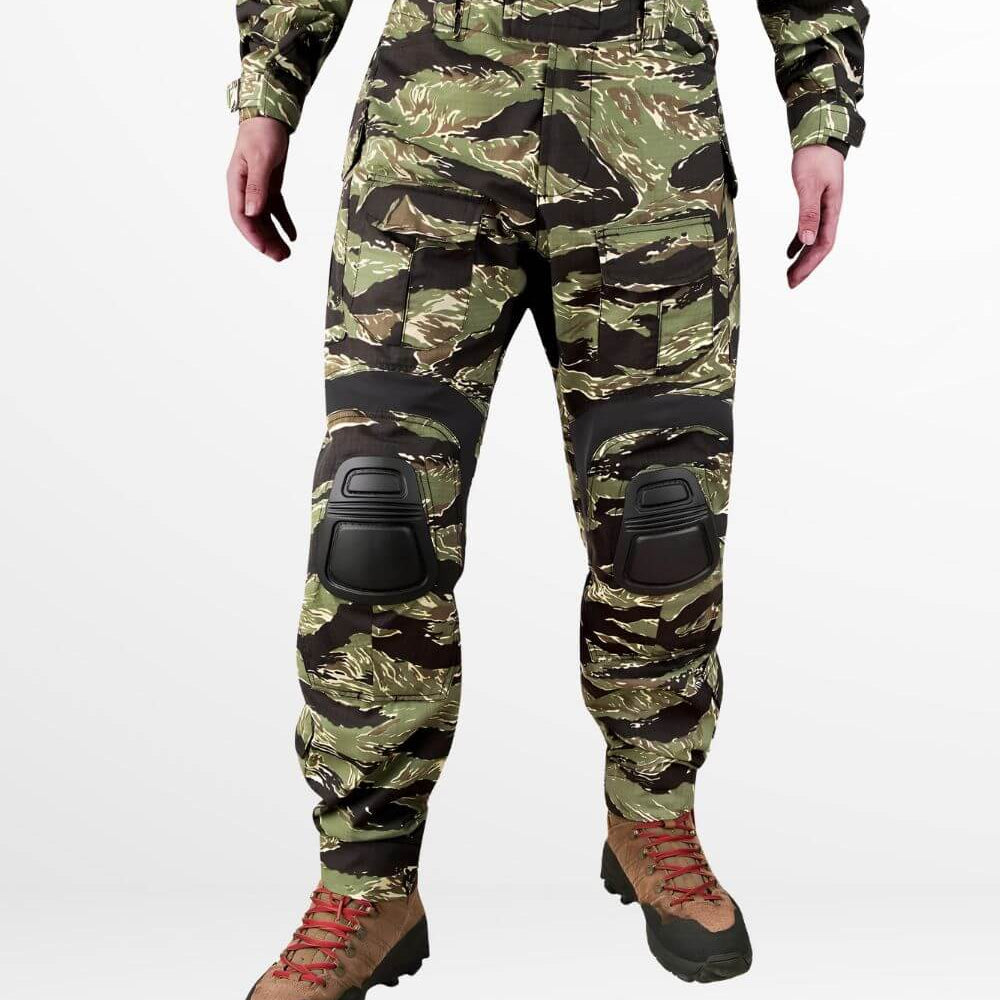 Front view of tiger stripe camo cargo pants with removable combat knee pads and tactical boot integration, perfect for outdoor adventures.