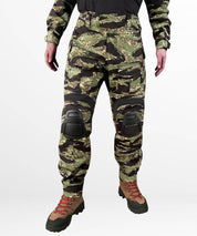 Front view of tiger stripe camo cargo pants with removable combat knee pads and tactical boot integration, perfect for outdoor adventures.