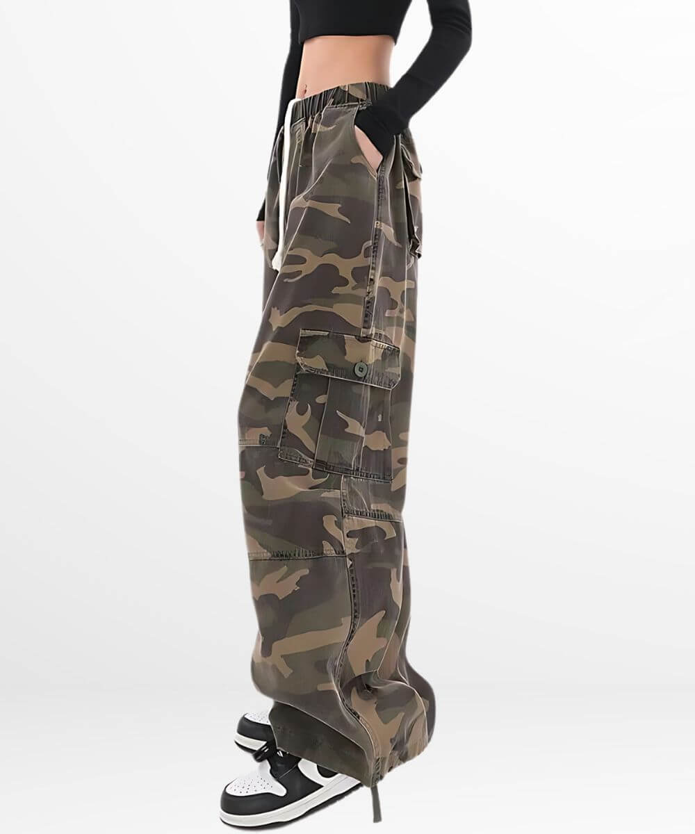 Side view of a woman in baggy camo pants showing the fit and flow of the fabric, paired with a black cropped top and sneakers.